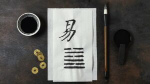 Chinese brushwork with ancient coins – symbolising knowledge, tradition, and discipline in Wing Chun.
