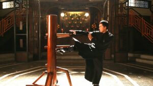 Ip Man practising Wing Chun on a wooden dummy inside a traditional training hall